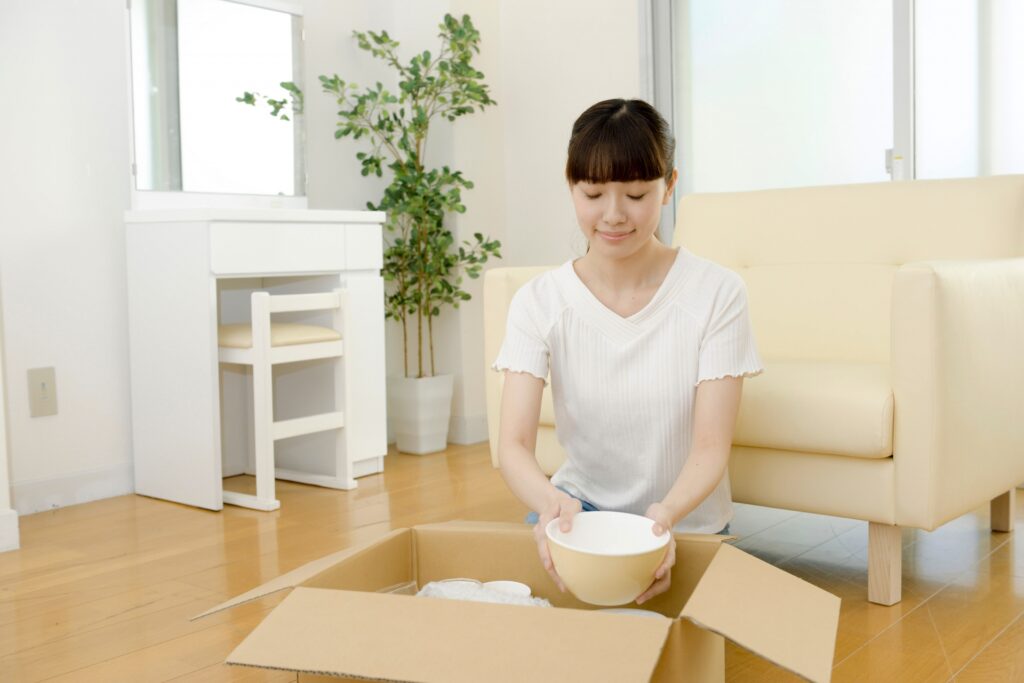 お皿を段ボールに入れる女性