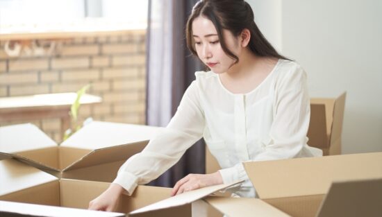 引っ越しで荷物をダンボールに詰める女性