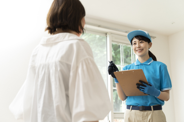 引っ越し業者と見積もりをとる女性